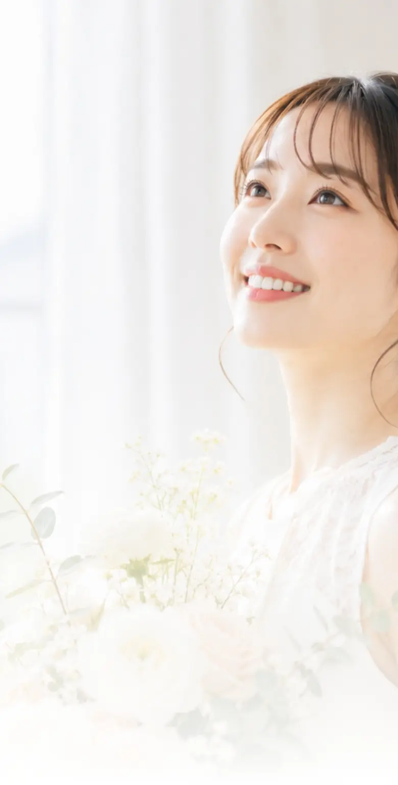 白いドレスを着てブーケを持ち、前を向いて微笑む女性