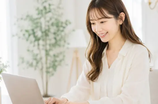 ノートパソコンを見ながら笑顔でプロフィールを作成する女性