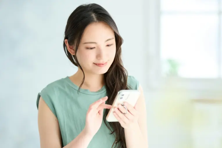 スマートフォンで婚活サービスを利用する女性